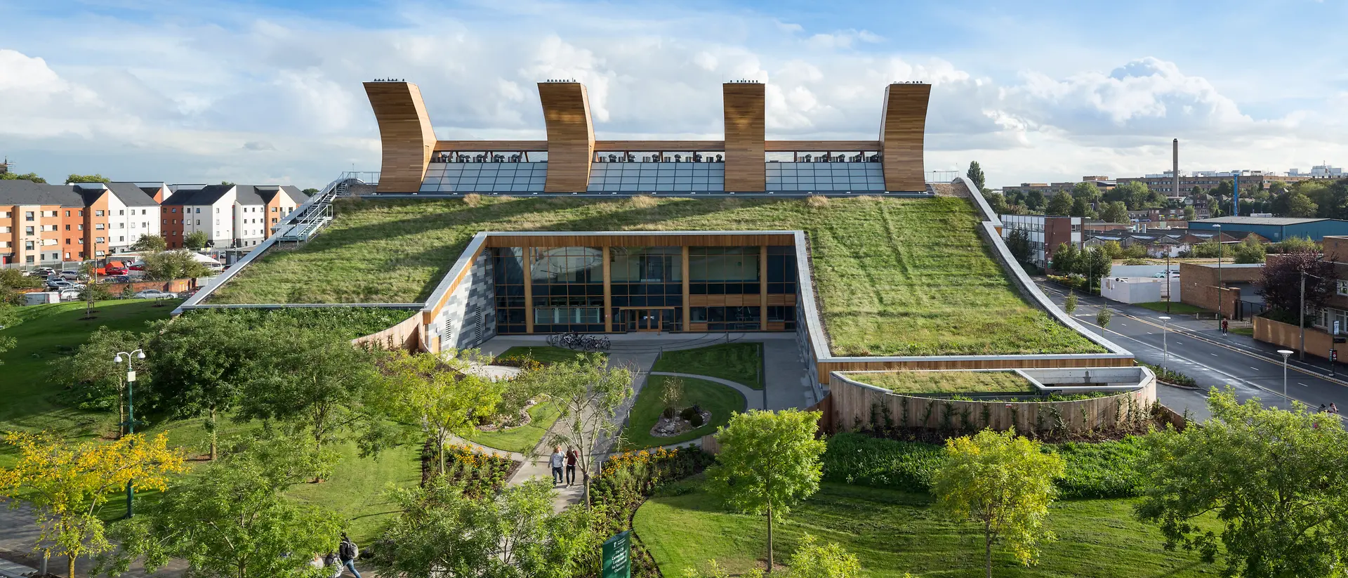 The Centre for Sustainable Chemistry: a glass and wood building with grass on the rooftop. It´s surrounded by a small park with trees.