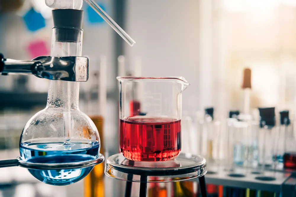 Three beakers filled with violett liquid on a laboratory desk represent our multiple techniques.