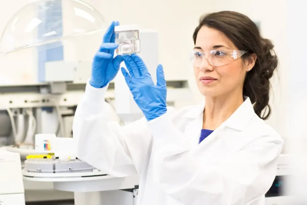 Woman in a laboratory with blue gloves holding a test dish