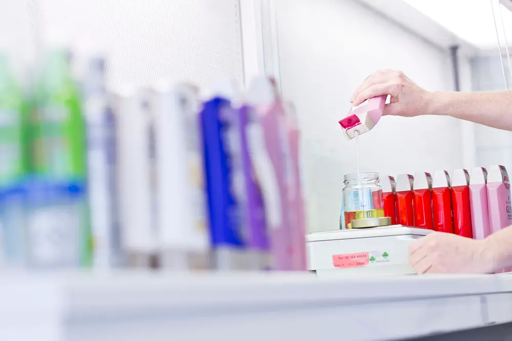 Henkel laundry products in the back, hand holding a detergent bottle 