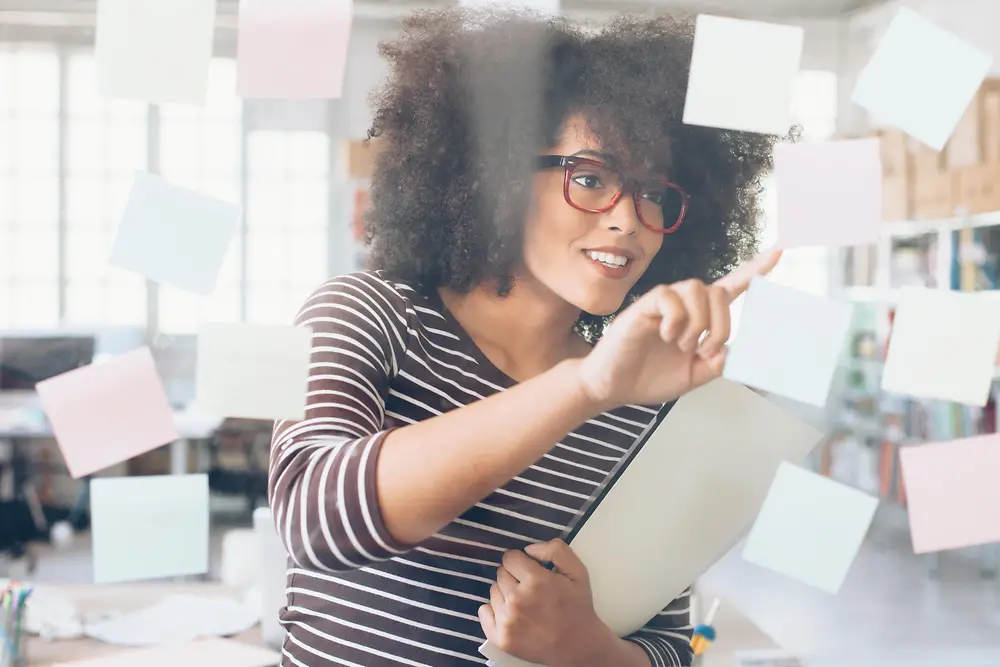 A woman looks at the taped post-its of a brainstorming session