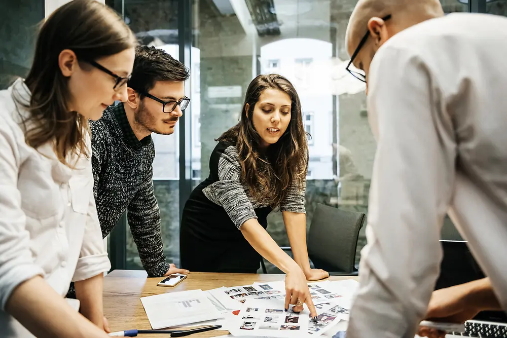 A group of four employees standing around a table and exchanging ideas.