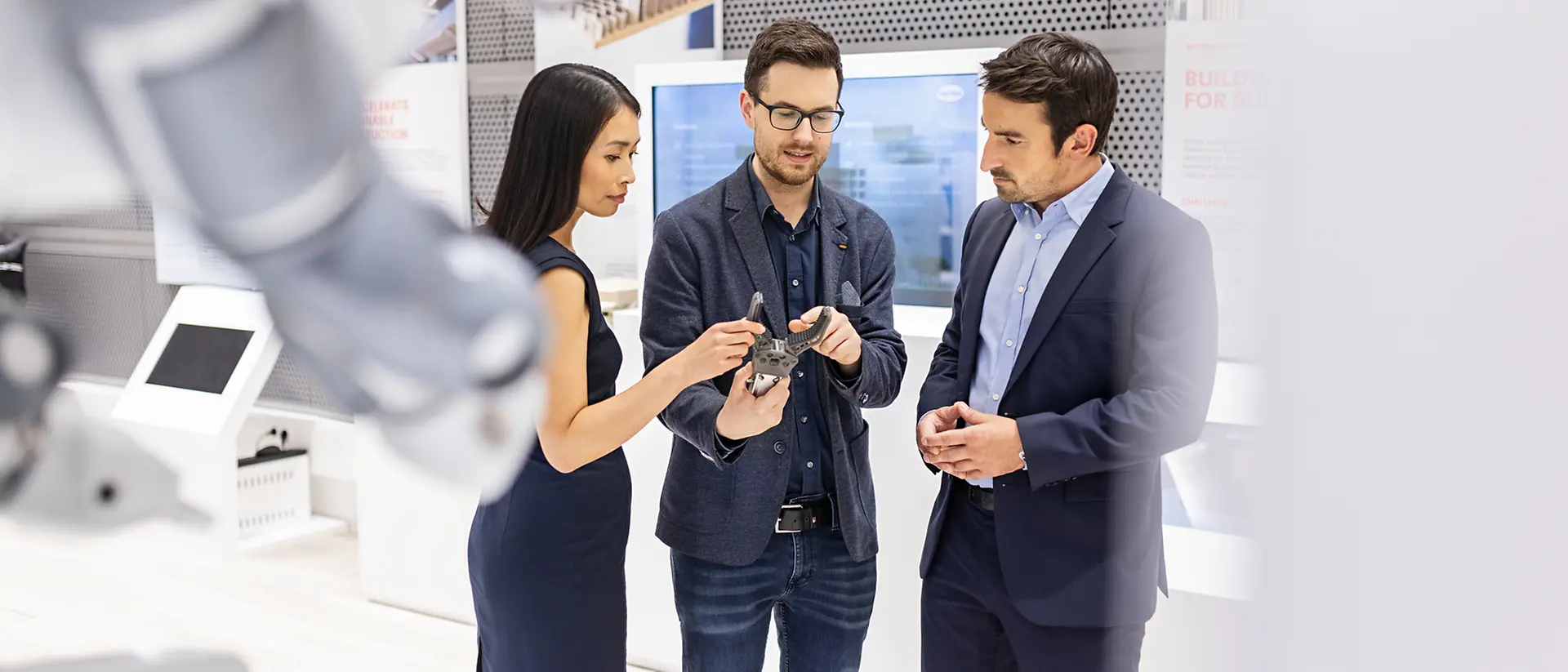 A customer experience tour guide presents application examples from Henkel Adhesive Technologies to two customers at the Inspiration Center Düsseldorf.