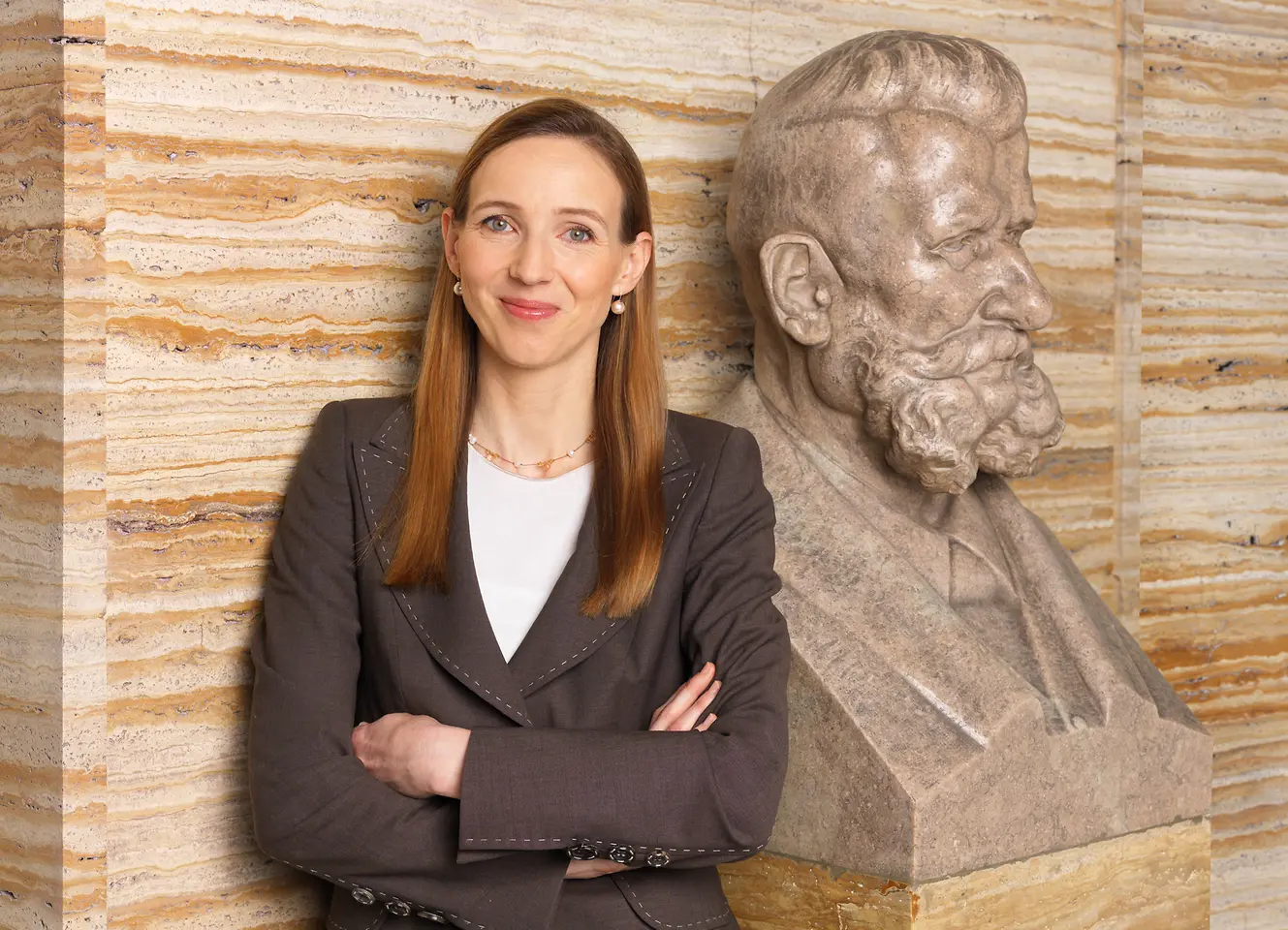 Dr. Simone Bagel-Trah (left) stands next to the bust of Fritz Henkel (right).