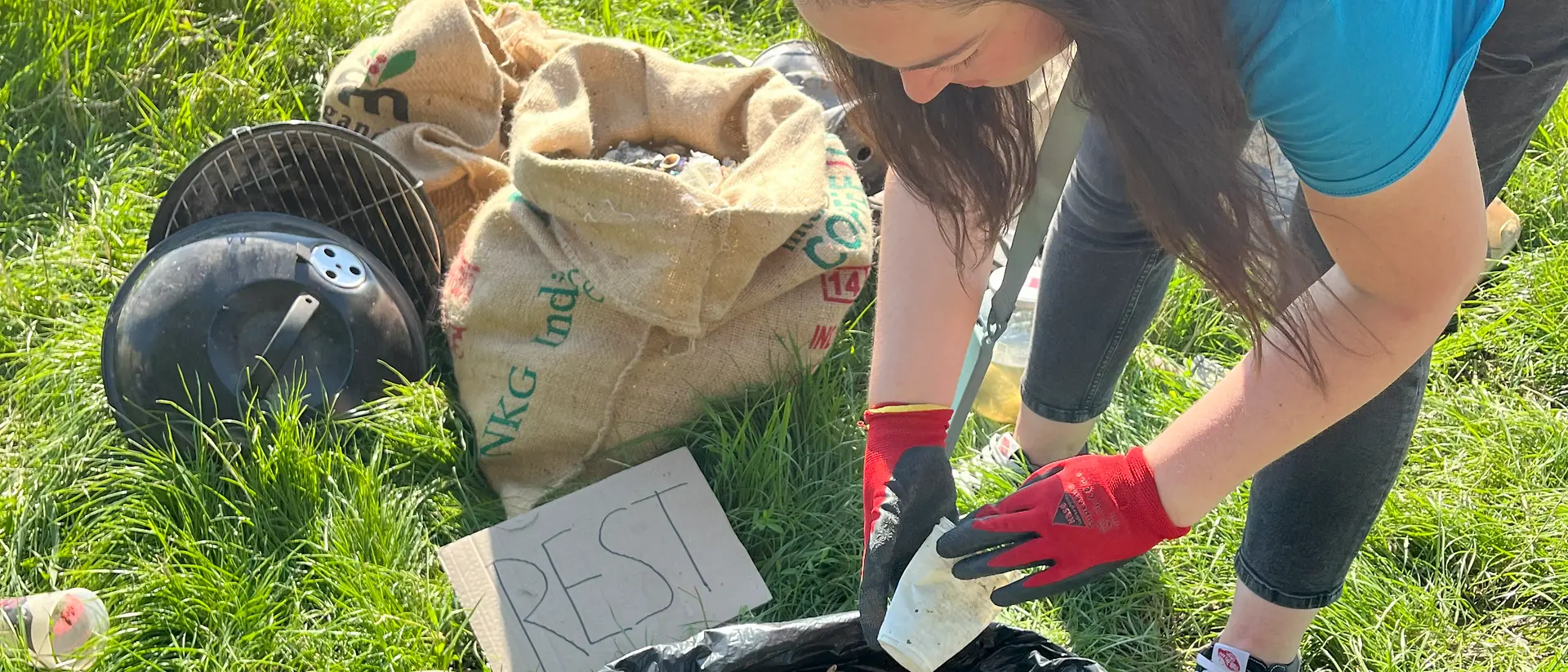 A woman throws a plastic cup into a thrash bag.