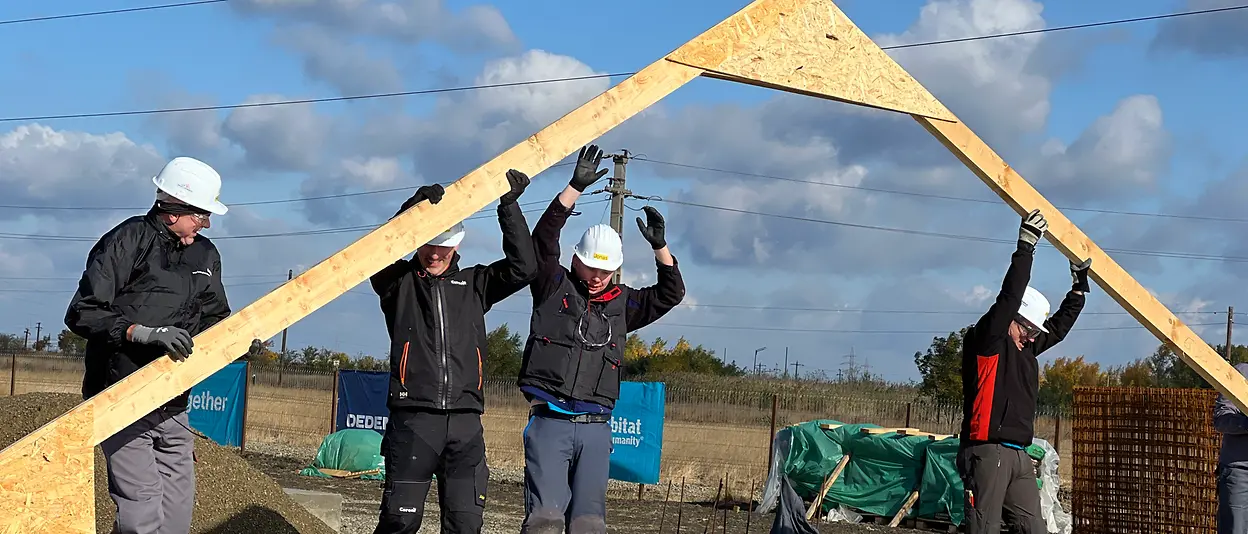 Several volunteers work together to put up the house’s wooden framework.