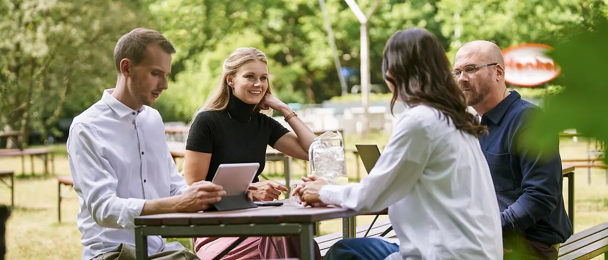 A group of people sitting at a table during an outdoor meeting.