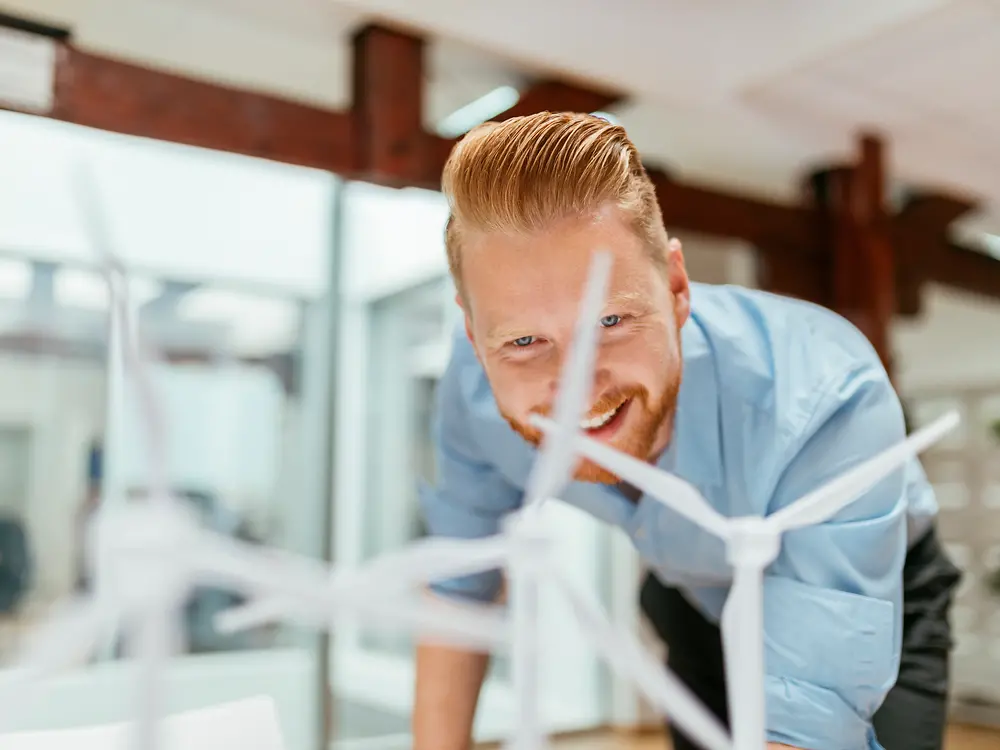 Businessman in office looking at models of wind turbines