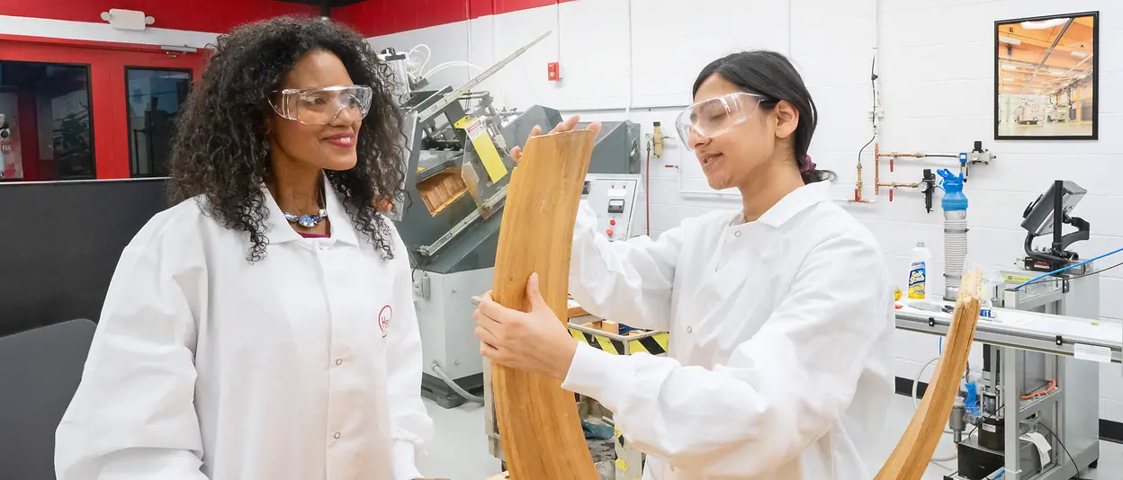 Two experts examine an application from Henkel Adhesive Technologies that is used for wood.