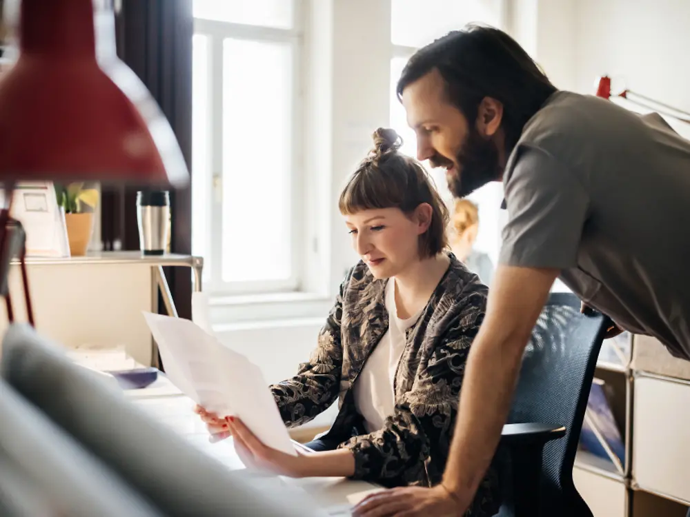 A man mentoring a female colleague.