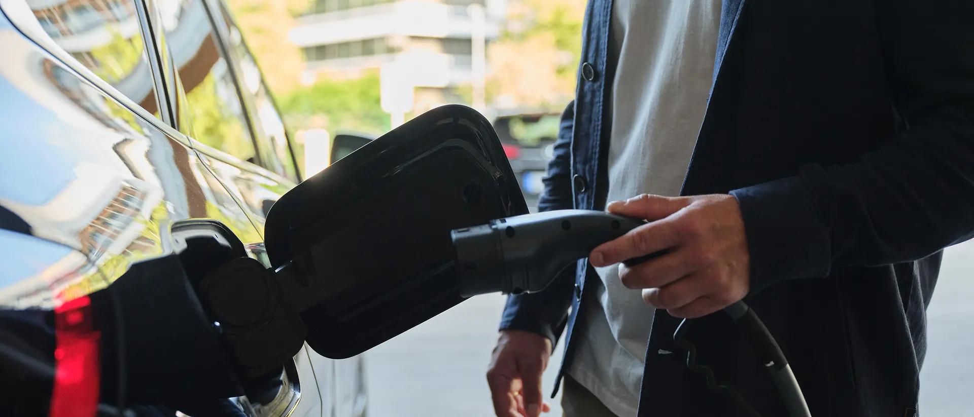 A man is about to connect his electric car to a charging station.