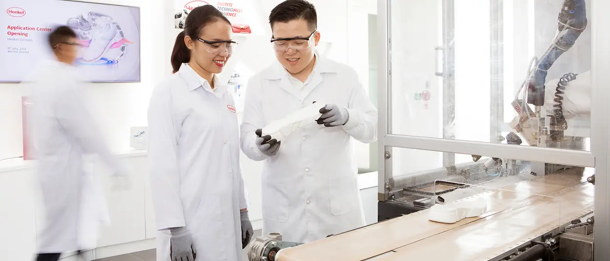 A man and a woman are standing in a laboratory at Henkel and test adhesive technologies that are used in the shoe industry.