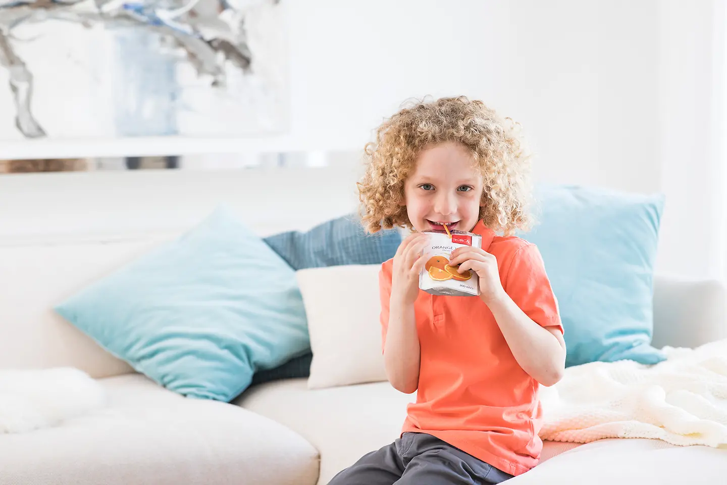 A smiling girl drinking from a package with straw